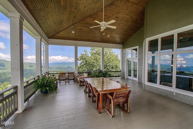 sunroom / solarium featuring ceiling fan, wooden ceiling, vaulted ceiling, and a mountain view