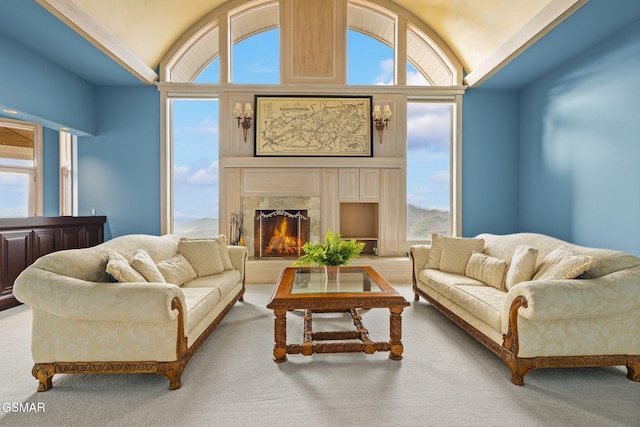 living room with a high end fireplace, a healthy amount of sunlight, and vaulted ceiling