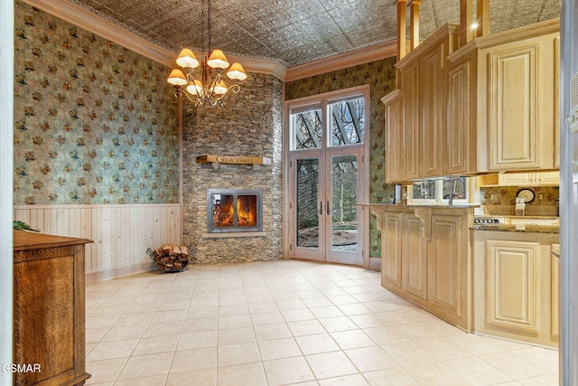 kitchen featuring an ornate ceiling, french doors, a wainscoted wall, crown molding, and wallpapered walls