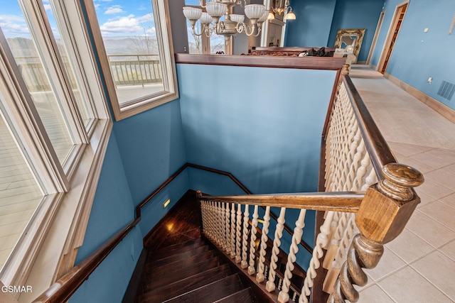 staircase with an inviting chandelier, tile patterned flooring, visible vents, and baseboards