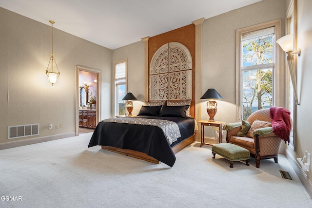 carpeted bedroom with baseboards, visible vents, and connected bathroom