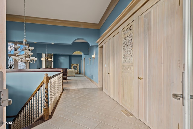 hallway featuring visible vents, arched walkways, ornamental molding, tile patterned floors, and a notable chandelier