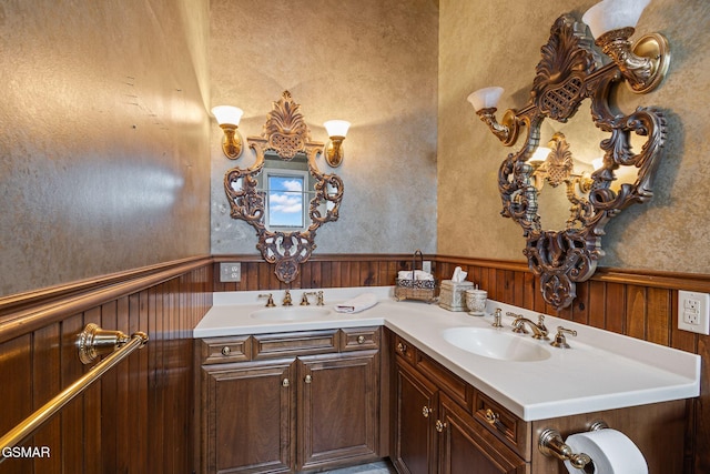 bathroom with a wainscoted wall, double vanity, and a sink