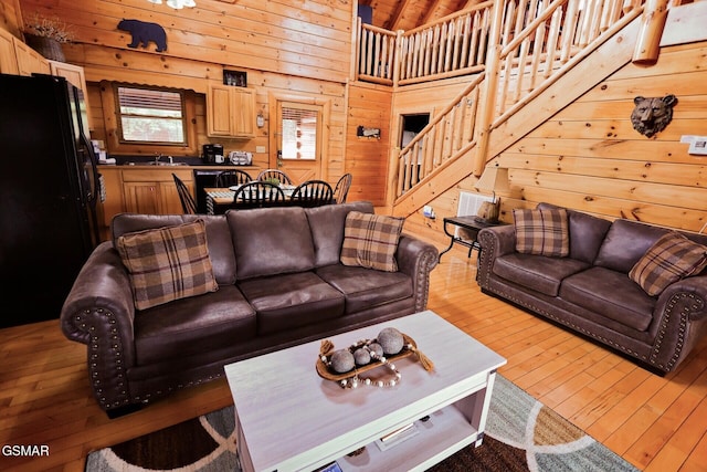 living area with stairs, light wood finished floors, and wooden walls