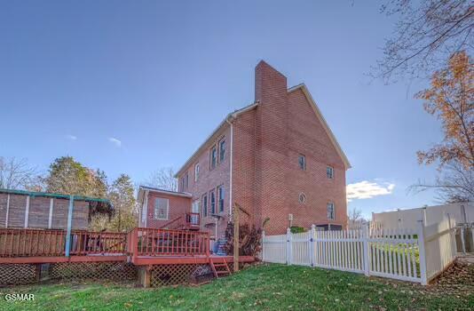 rear view of property featuring a lawn and a wooden deck