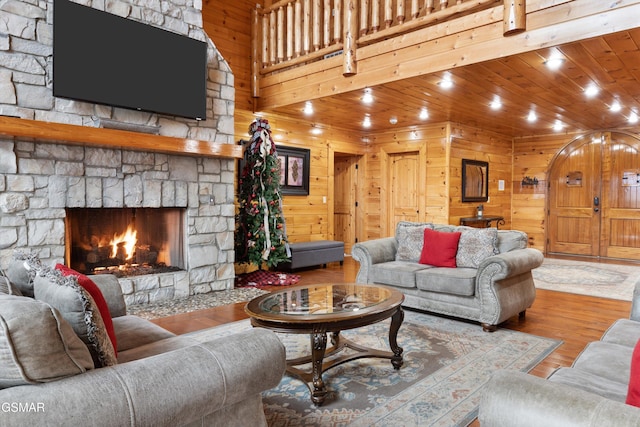 living room with wooden walls, hardwood / wood-style floors, a fireplace, and wood ceiling