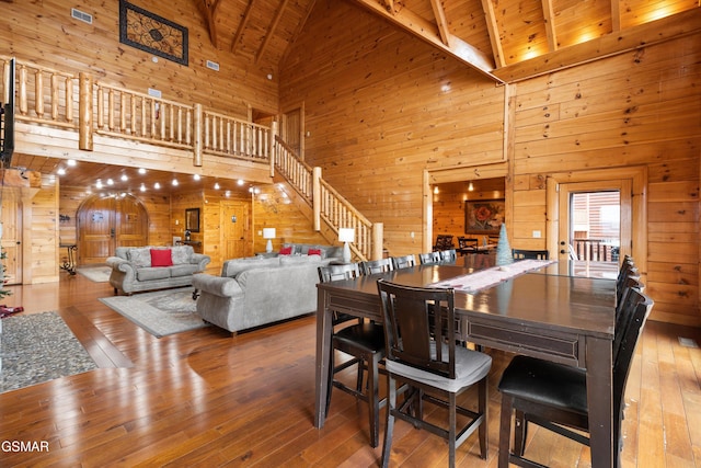 dining room with wood ceiling, high vaulted ceiling, wooden walls, beam ceiling, and hardwood / wood-style floors