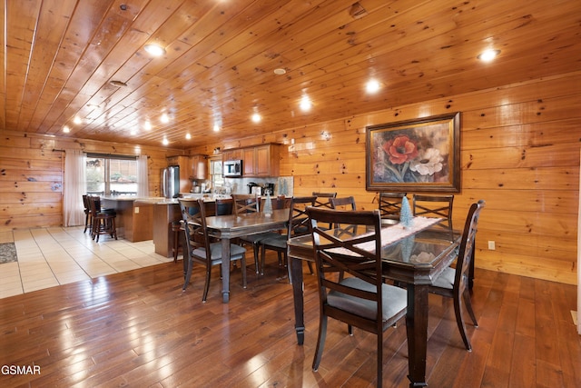 dining room with wooden ceiling, light hardwood / wood-style floors, and wood walls