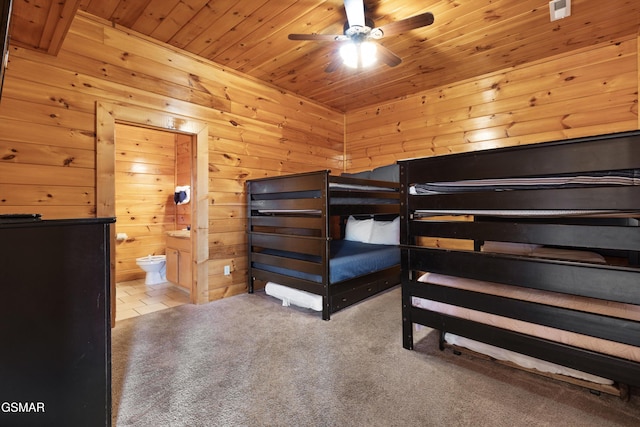 unfurnished bedroom featuring ensuite bathroom, wooden walls, light colored carpet, ceiling fan, and wood ceiling