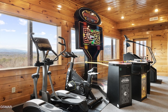 exercise area featuring wood ceiling, wooden walls, a mountain view, and carpet