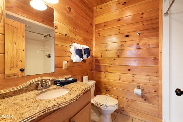 bathroom featuring toilet, a shower, vanity, wooden walls, and tile patterned flooring