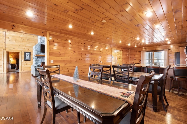 dining space with wood ceiling, wood-type flooring, and a stone fireplace