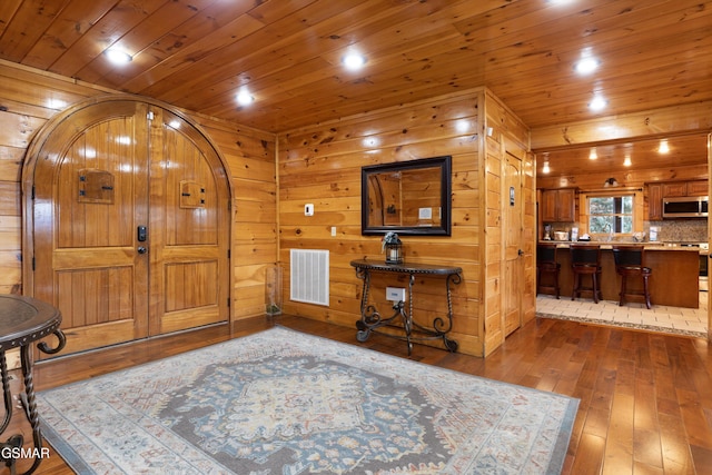 foyer entrance featuring hardwood / wood-style flooring, wood walls, and wooden ceiling