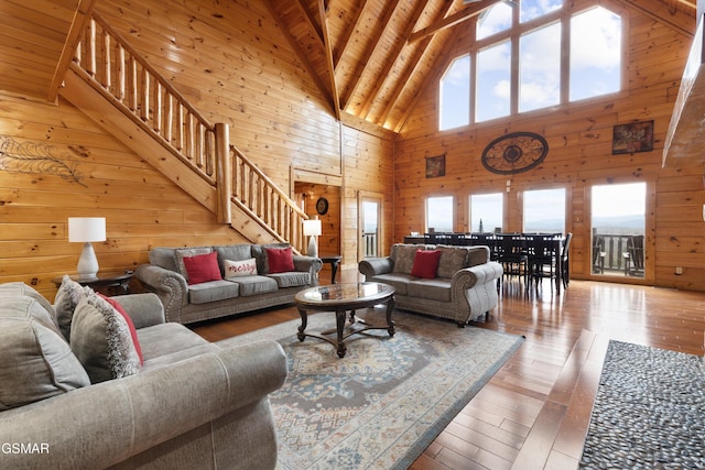 living room featuring wooden walls, high vaulted ceiling, wood-type flooring, wood ceiling, and beam ceiling