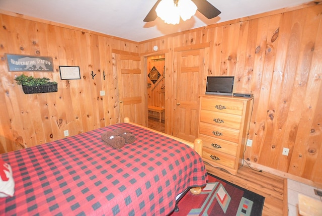 bedroom with ceiling fan and wood walls