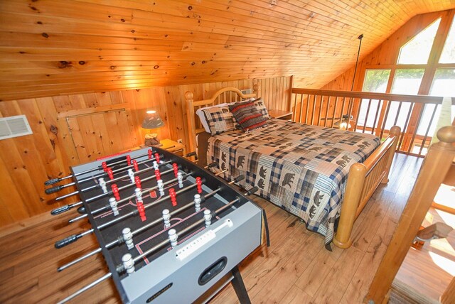 bedroom featuring wood ceiling, light hardwood / wood-style flooring, wooden walls, and vaulted ceiling