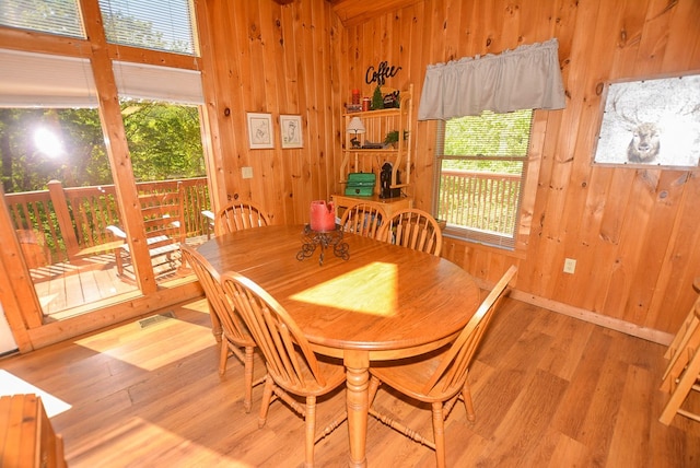 dining room featuring a wealth of natural light, wood walls, and hardwood / wood-style flooring