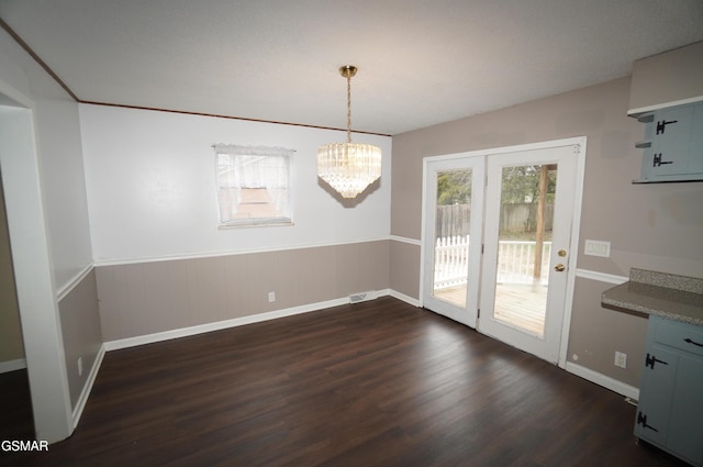 unfurnished dining area with a notable chandelier and dark wood-type flooring