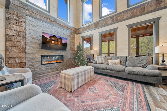 living room with a wealth of natural light, wood walls, a fireplace, and a towering ceiling