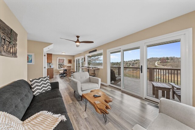 living room with baseboards, light wood-style floors, visible vents, and ceiling fan