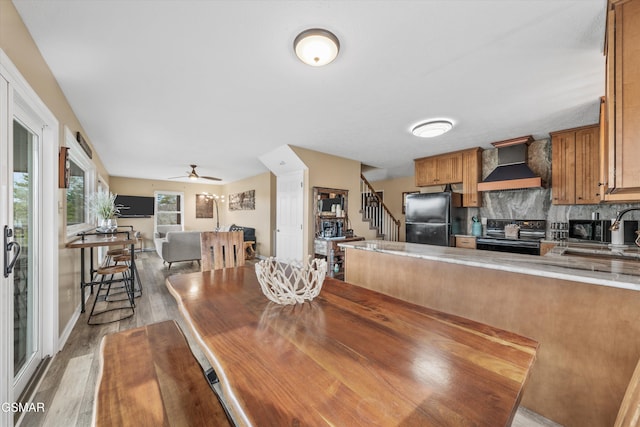 dining room with stairway, baseboards, light wood-type flooring, and ceiling fan