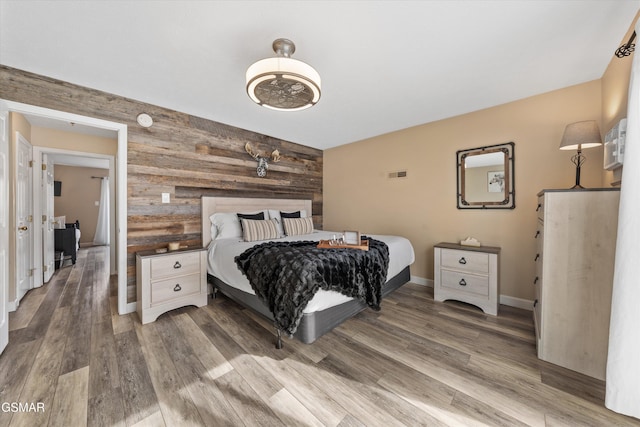 bedroom featuring wood walls, baseboards, and wood finished floors