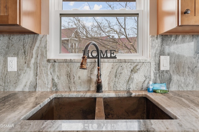 details with light stone countertops, backsplash, and a sink