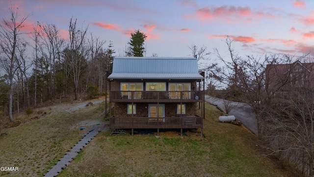 back of house with metal roof, a yard, a wooden deck, and driveway