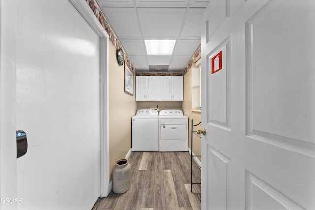 washroom featuring cabinet space, wood finished floors, and separate washer and dryer