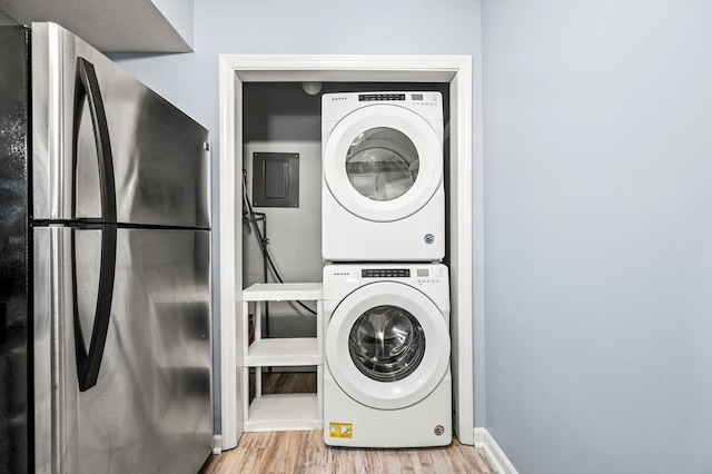 washroom with stacked washer / dryer, electric panel, and light hardwood / wood-style floors