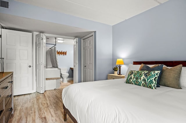 bedroom with ensuite bath and hardwood / wood-style floors