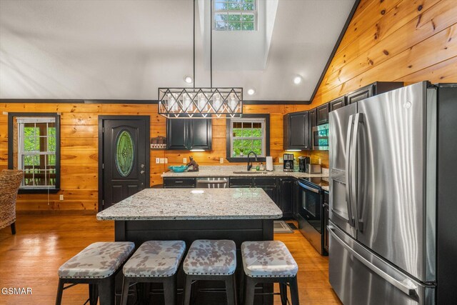 380 Laurel Rd, Townsend, TN 37882 - kitchen featuring stainless steel appliances, a sink, wooden walls, light wood-type flooring, and a center island