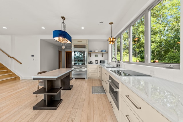 3661 Richardson Cove Rd, Sevierville, TN 37876 - kitchen featuring light stone countertops, sink, pendant lighting, black electric cooktop, and light wood-type flooring