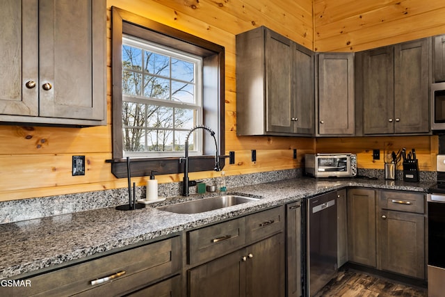 kitchen featuring a toaster, wood walls, appliances with stainless steel finishes, and a sink