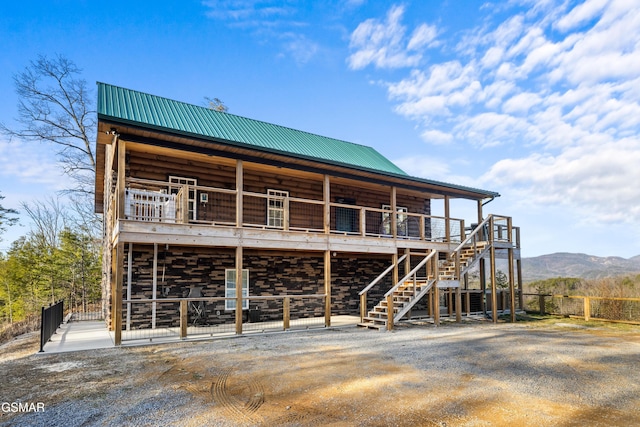 back of house featuring metal roof, a mountain view, and stairs