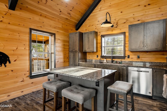 kitchen with wood walls, dishwasher, lofted ceiling with beams, and a sink