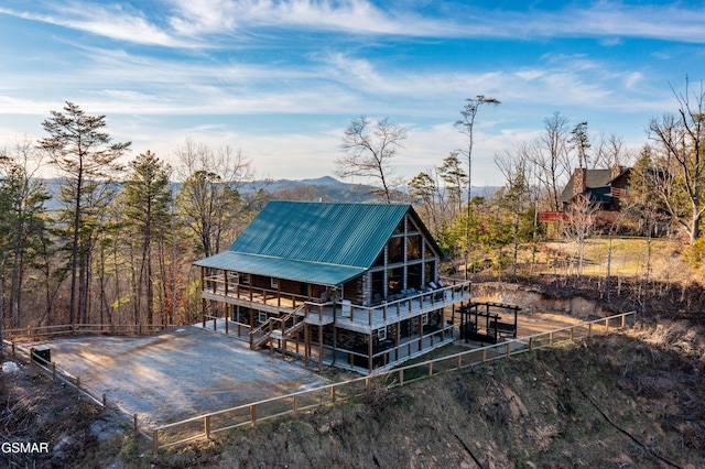 back of property featuring fence, driveway, and metal roof