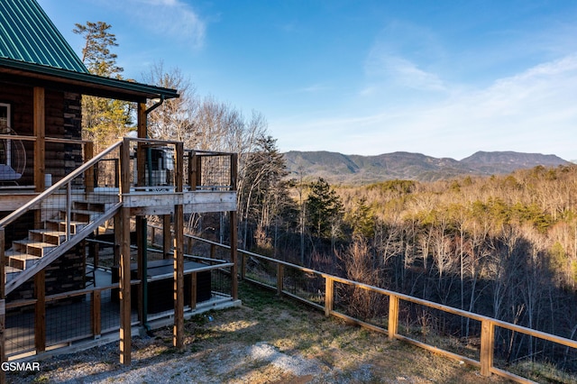 view of yard with stairway, a deck with mountain view, and fence