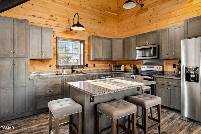 kitchen featuring stainless steel appliances, wooden walls, a breakfast bar area, and a center island