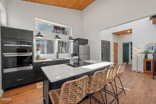 2385 Forge Hideaway Loop Unit 4, Pigeon Forge, TN 37863 - kitchen with stainless steel appliances, a sink, a kitchen breakfast bar, light wood-style flooring, and a towering ceiling