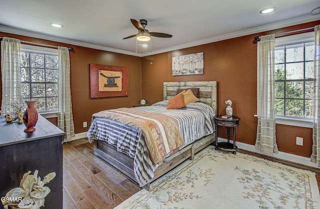 bedroom featuring a ceiling fan, crown molding, baseboards, and wood finished floors