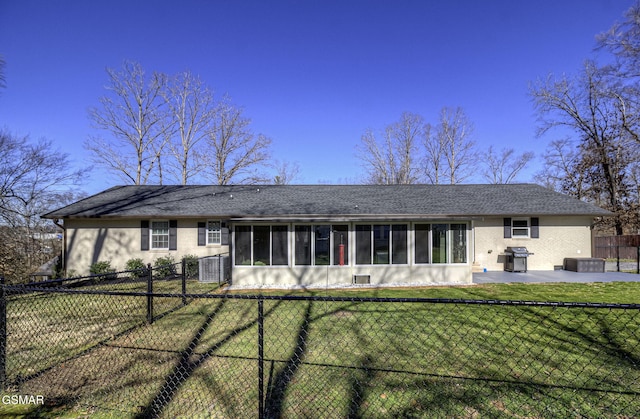 view of front of house featuring a fenced backyard, a patio area, a front yard, and a sunroom