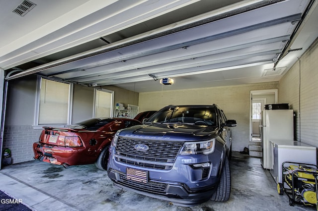 garage featuring visible vents, a garage door opener, and freestanding refrigerator