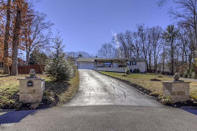 view of front facade featuring a garage, driveway, a front yard, and fence