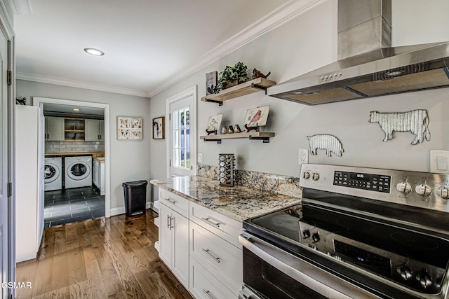 kitchen with dark wood-type flooring, wall chimney range hood, stainless steel electric stove, ornamental molding, and independent washer and dryer