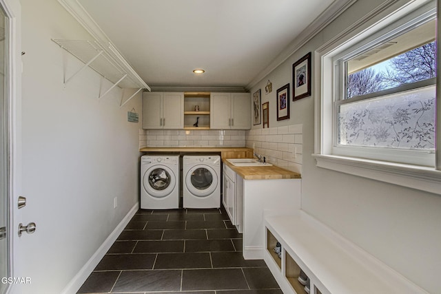 laundry area with dark tile patterned flooring, cabinet space, separate washer and dryer, a sink, and crown molding