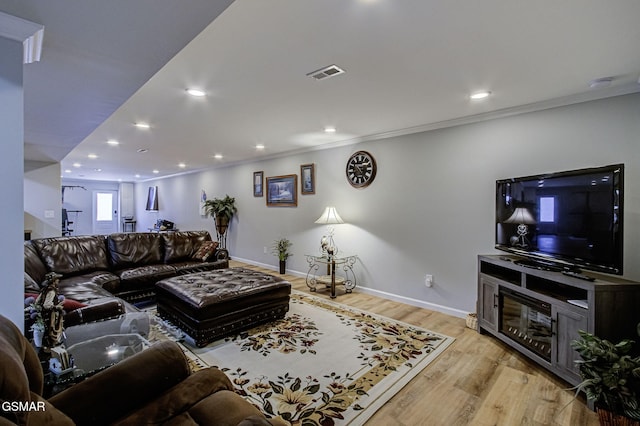 living room featuring crown molding, light wood-style floors, visible vents, and baseboards