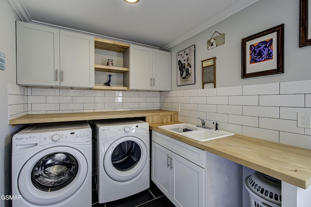 clothes washing area with a sink, cabinet space, washing machine and dryer, and crown molding