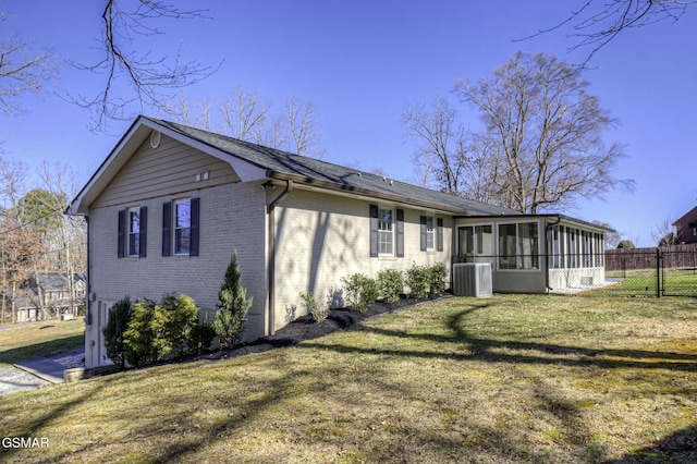 exterior space featuring a lawn, fence, cooling unit, a sunroom, and brick siding