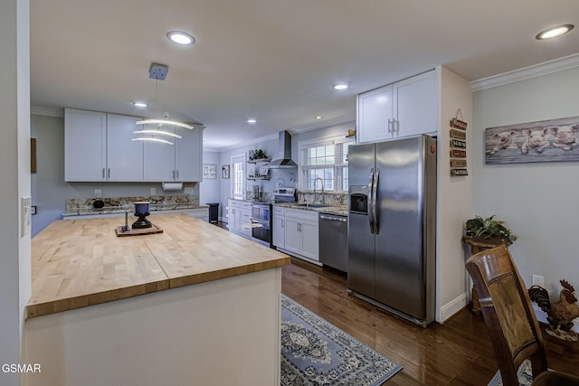 kitchen featuring wall chimney range hood, ornamental molding, appliances with stainless steel finishes, wood counters, and a sink